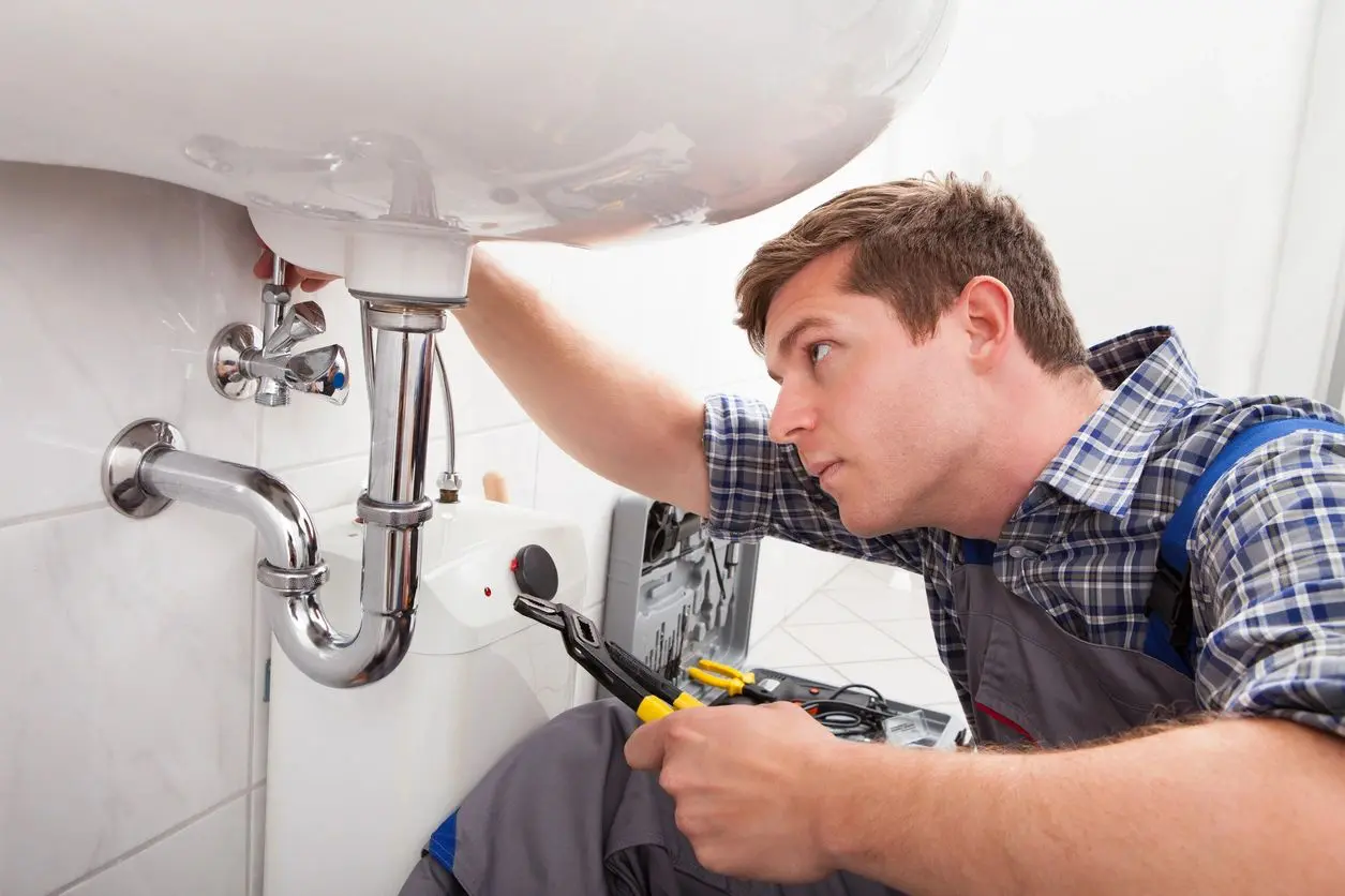 A man fixing the pipes of a sink.